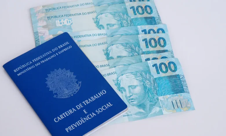 Carteira de Trabalho e notas de 100 reais representando direitos trabalhistas