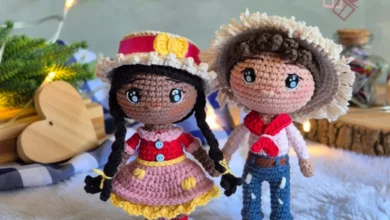 Casal de bonecos amigurumi em estilo junino com roupas típicas e decoração festiva ao fundo
