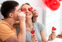 Casal feliz brincando com corações vermelhos para comemorar o Dia dos Namorados em casa