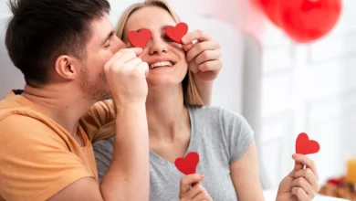 Casal feliz brincando com corações vermelhos para comemorar o Dia dos Namorados em casa