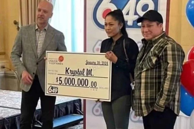 Pessoa segurando um cheque simbólico de 5 milhões de dólares em cerimônia de premiação da loteria.