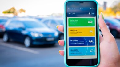 Pessoa segura celular com o app CDT aberto exibindo opções digitais para condutores e veículos