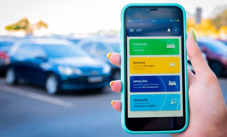 Pessoa segura celular com o app CDT aberto exibindo opções digitais para condutores e veículos