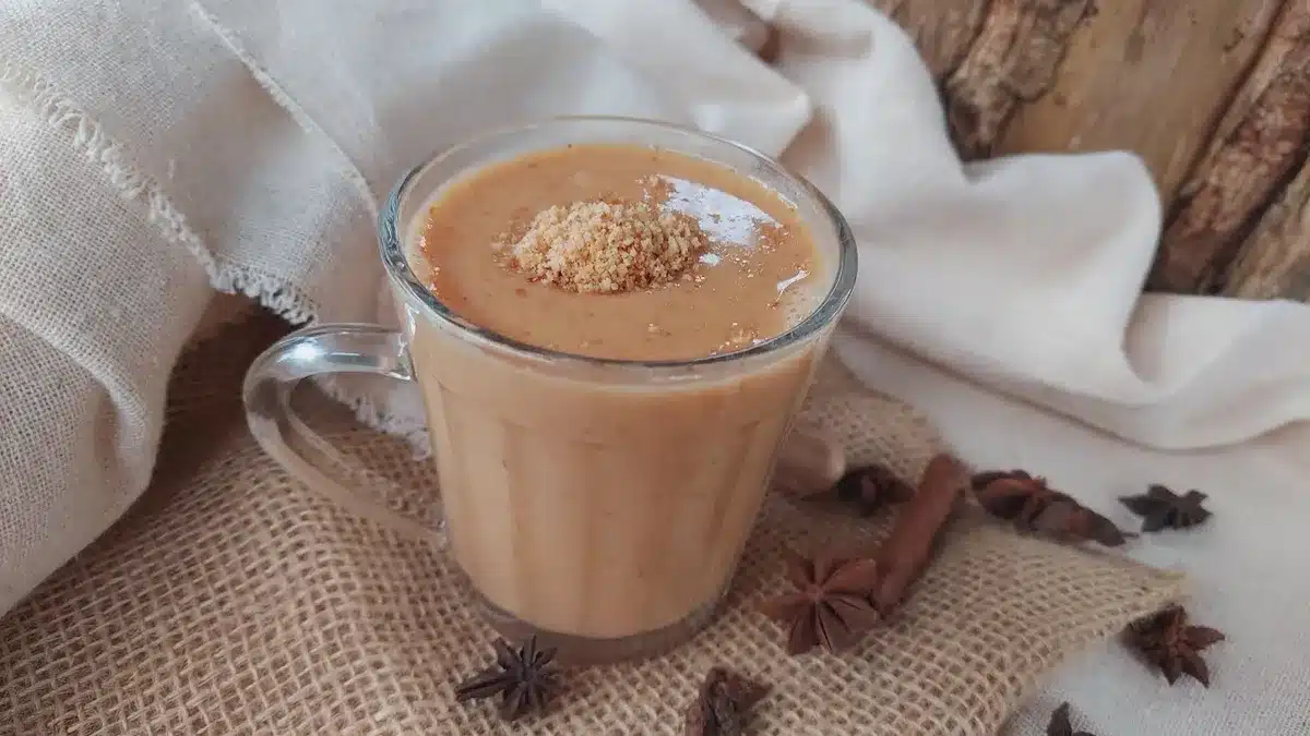 Copo de chá de amendoim cremoso decorado com amendoim triturado, com fundo de decoração junina.