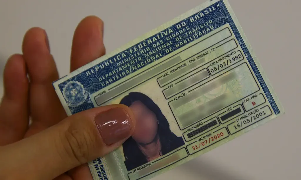 Mão segurando uma CNH impressa no modelo antigo, representando o acesso ao documento