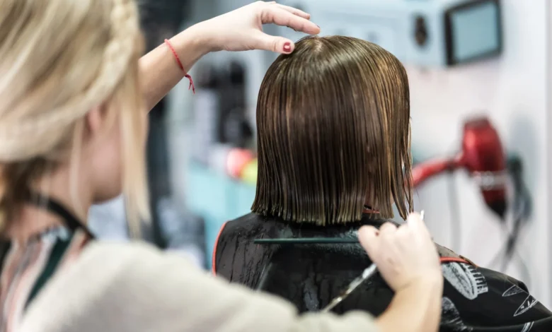 Cabeleireiro cortando cabelo curto de mulher em um salão de beleza, com foco em técnicas modernas de corte.