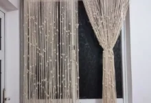 Cortina de crochê feita à mão com fios naturais e detalhes delicados, pendurada em uma janela.
