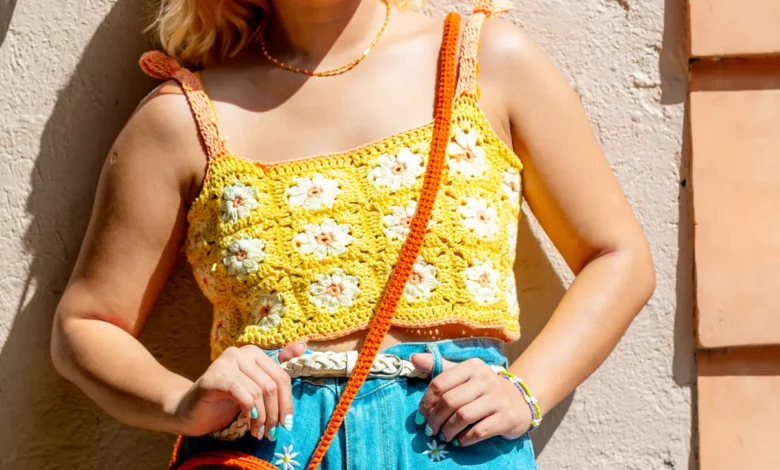 cropped de crochĂȘ Blusa de crochĂȘ amarela com flores coloridas, detalhes em laranja, e acessĂłrios combinando em um look casual e vibrante.
