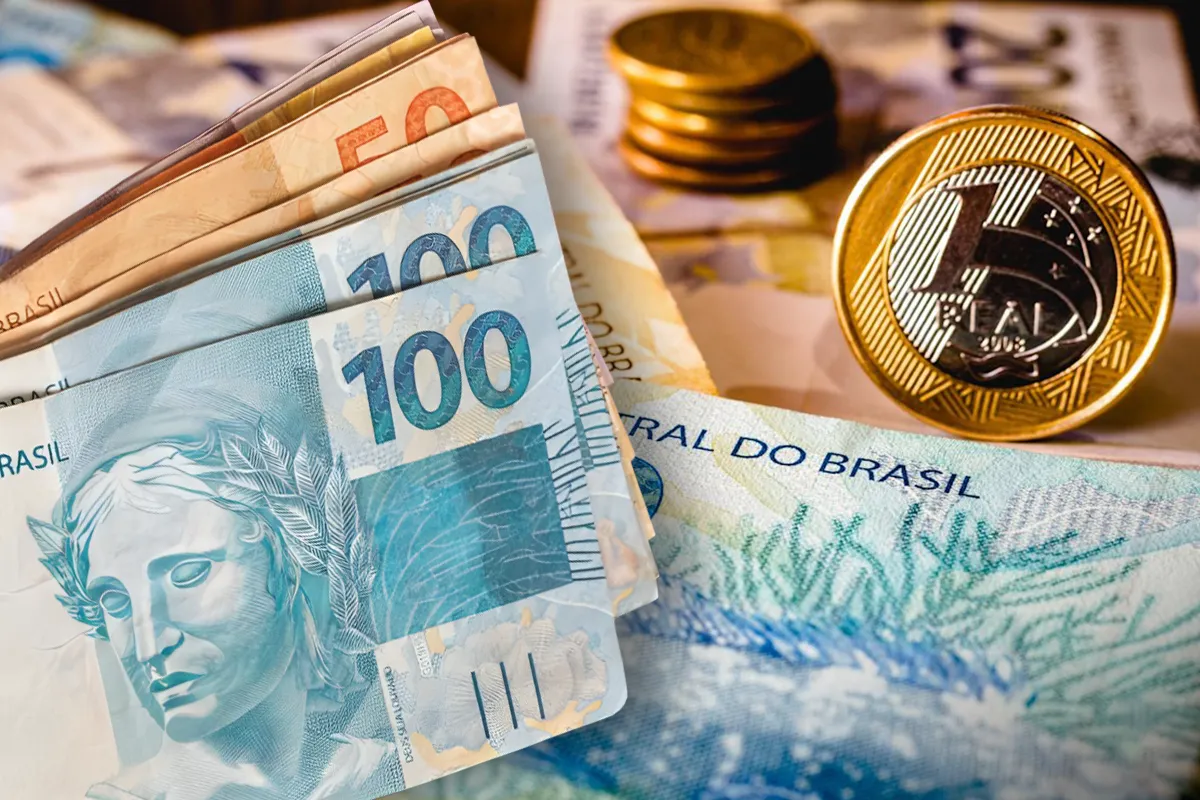 Imagem ilustrativa sobre valores a receber, mostrando cédulas de 50 e 100 reais e moedas em reais.