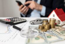 Elementos representando finanças, como moedas, casa em miniatura, carro e calculadora