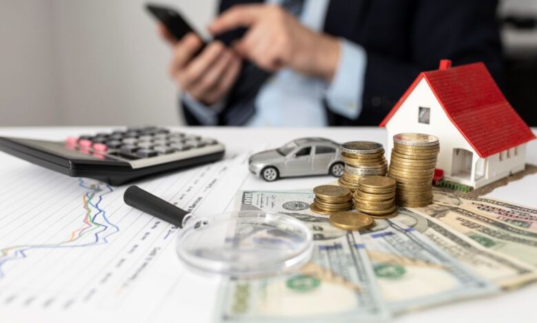 Elementos representando finanças, como moedas, casa em miniatura, carro e calculadora
