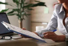 Mulher preenchendo formulário com documentos em escritório, representando os papéis exigidos para o Minha Casa Minha Vida 2025