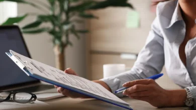Mulher preenchendo formulário com documentos em escritório, representando os papéis exigidos para o Minha Casa Minha Vida 2025