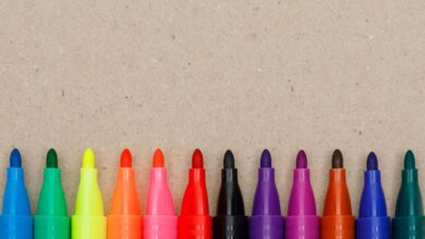 Canetinhas coloridas enfileiradas sobre uma superfície de papel, usadas para colorir livros como os da Bobbie Goods.