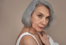 Mulher com cabelo grisalho em estilo moderno, refletindo a tendência da moda dos grisalhos, aos 50 anos.