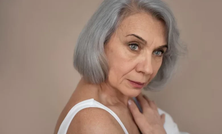 Mulher com cabelo grisalho em estilo moderno, refletindo a tendência da moda dos grisalhos, aos 50 anos.