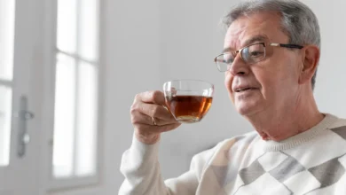 Senhor idoso apreciando uma xícara de chá em ambiente iluminado, simbolizando saúde e bem-estar na terceira idade.