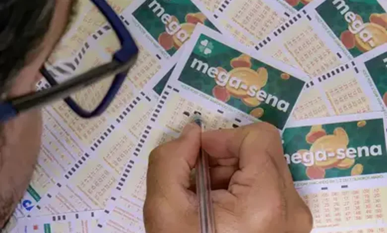 Pessoa preenchendo bilhete da Mega-Sena, com vários bilhetes ao fundo