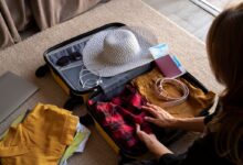 Mulher organizando mala de viagem com roupas, acessórios e itens essenciais