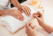 Aplicação de esmalte claro em unhas bem cuidadas durante sessão de manicure