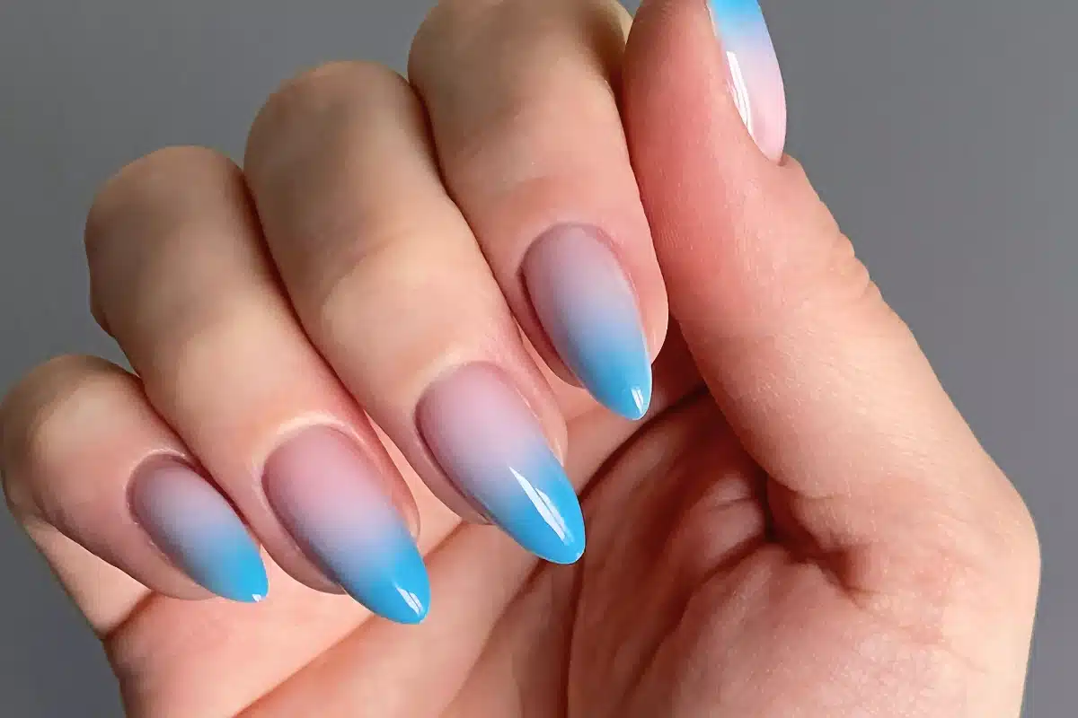 Unhas decoradas com esmalte degradê azul, manicure elegante e moderna.