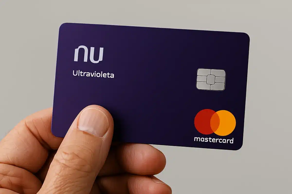 Mão idosa segurando cartão de crédito Nubank Ultravioleta.