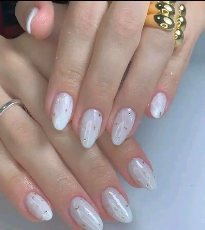 Unhas marmorizadas brancas com detalhes dourados, um design elegante e sofisticado.
