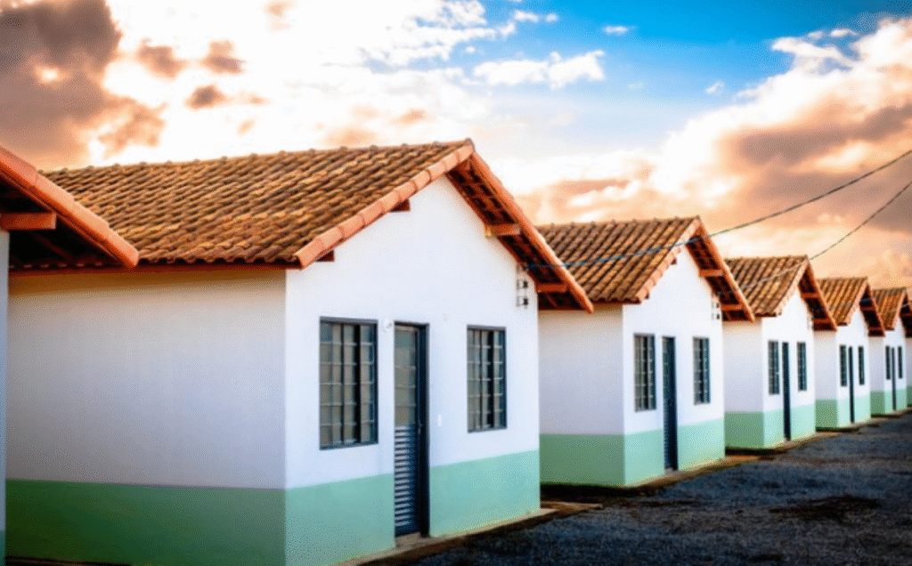 Imagem de unidades habitacionais construídas, com telhados de cerâmica e pintura nas cores branca e verde, ilustrando o programa habitacional da prefeitura.