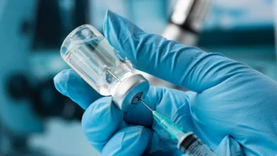 Profissional de saúde manipulando frasco e seringa de vacina contra meningite