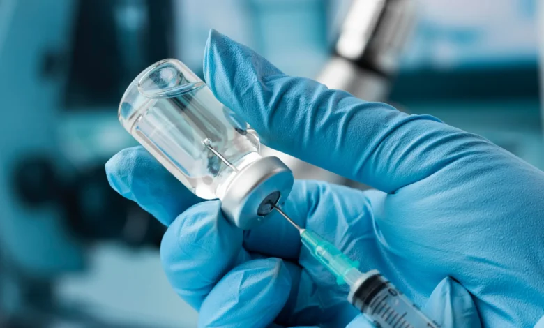 Profissional de saúde manipulando frasco e seringa de vacina contra meningite