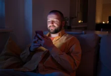 Homem enviando mensagem de boa noite pelo celular antes de dormir