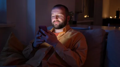Homem enviando mensagem de boa noite pelo celular antes de dormir