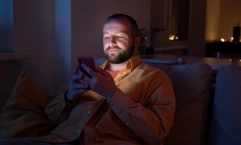 Homem enviando mensagem de boa noite pelo celular antes de dormir