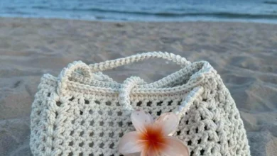 Bolsa de crochê com flor de plumeria em fundo de praia
