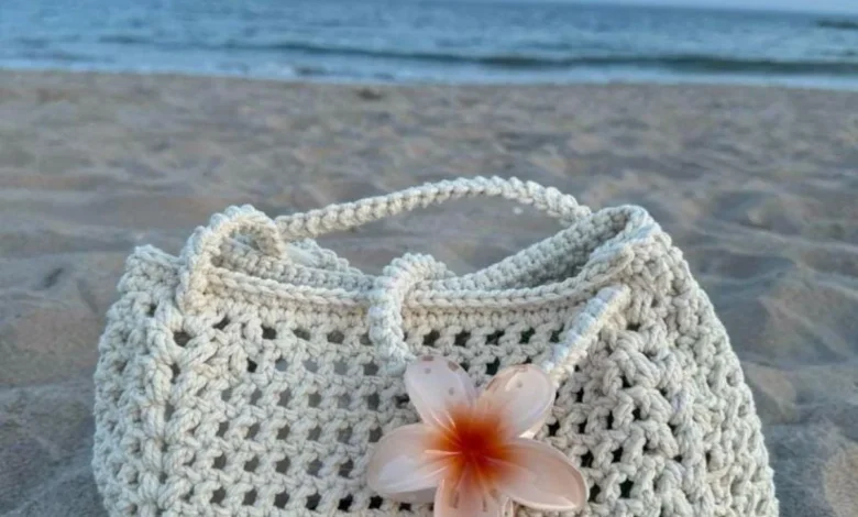 Bolsa de crochê com flor de plumeria em fundo de praia
