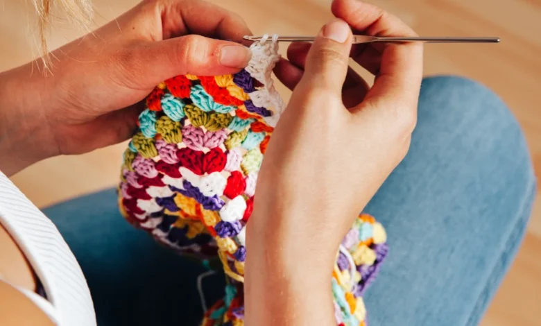 Mulher crochetando peça colorida com agulha de crochê