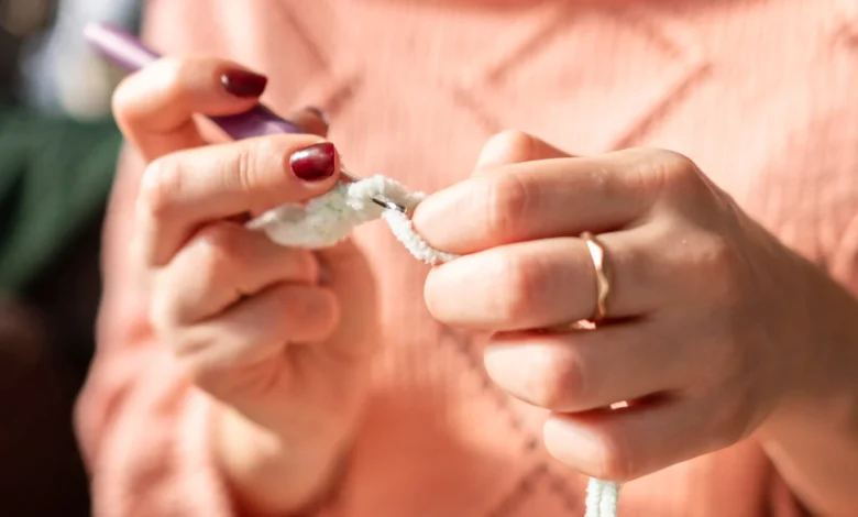 Mulher fazendo crochê com fio branco, usando técnica para criar texturas