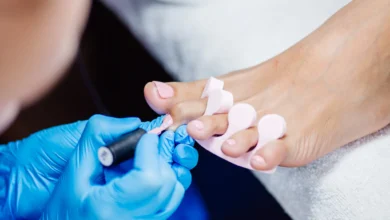 Aplicação de esmalte de gel rosa claro em unhas dos pés, um processo de pedicure profissional.