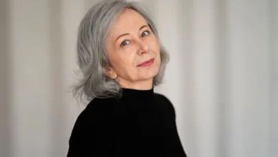 Mulher de cabelo curto grisalho, usando blusa preta, com expressão suave e confiante.