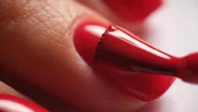 Aplicação precisa de esmalte vermelho vibrante em unha.