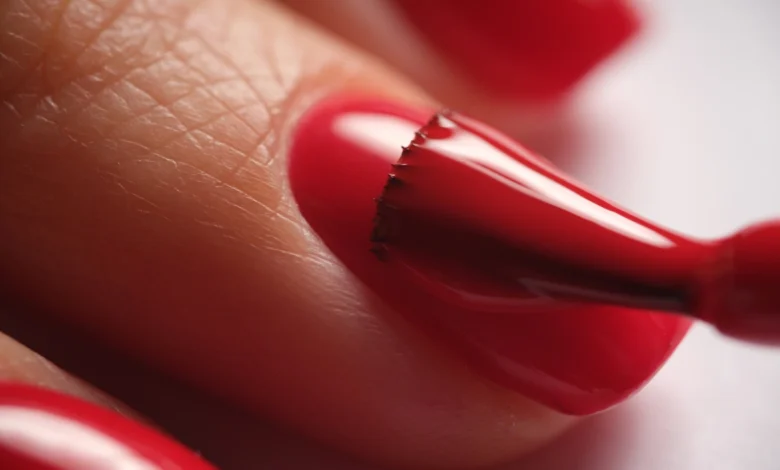 Aplicação precisa de esmalte vermelho vibrante em unha.
