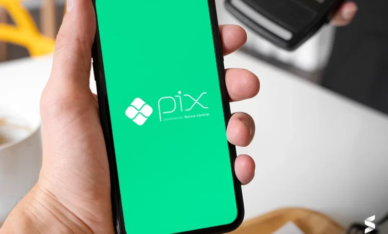 Pessoa usando o Pix em um smartphone com a tela verde exibindo o logo do Banco Central.