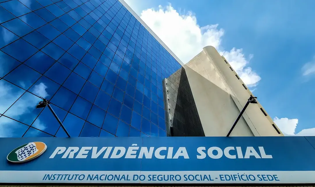 Fachada do prédio da Previdência Social com vidro refletindo o céu, destacando a instituição responsável pelos benefícios sociais no Brasil.
