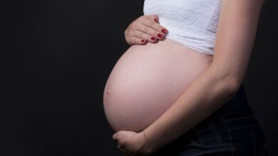 Mulher grávida segurando a barriga com fundo escuro