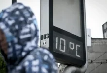Termômetro marcando 10 graus Celsius em rua urbana no início do inverno.