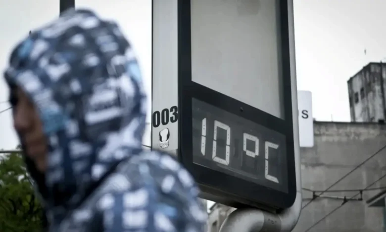 Termômetro marcando 10 graus Celsius em rua urbana no início do inverno.