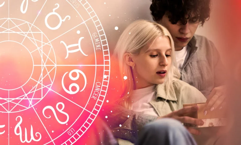 Casal jovem lendo previsões amorosas com roda zodiacal ao fundo