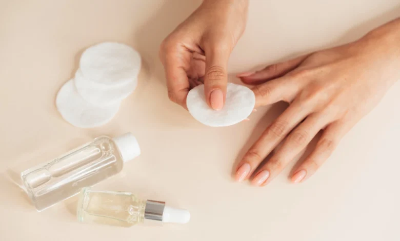 Mãos femininas com unhas cuidadas usando algodão para remover esmalte sem acetona