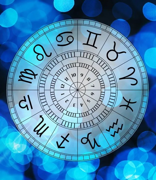 Imagem da roda do zodíaco com os 12 signos astrológicos em fundo de bokeh azul.