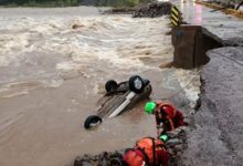 Equipe de resgate atua em área alagada com carro submerso após rompimento de estrada